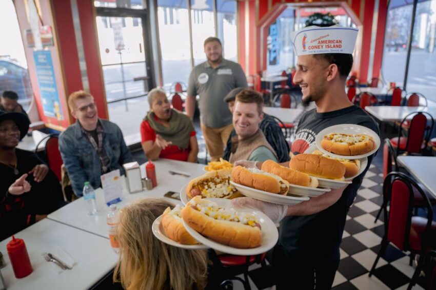 Waiter serving hotdogs to customers in American Coney Island restaurant